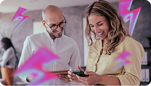 A man and a woman look at a smartphone and laugh, surrounded by pink lightning bolts.