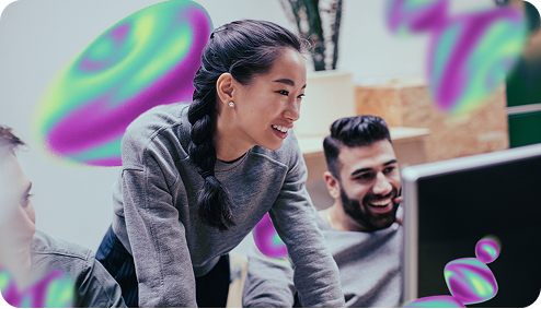 Two people smile as they look at a computer screen with colorful graphics.