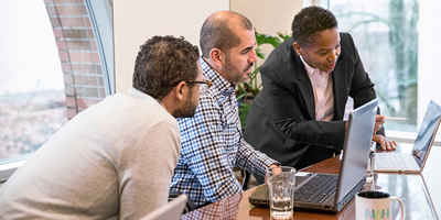 Tres personas mirando el notebook sobre la mesa