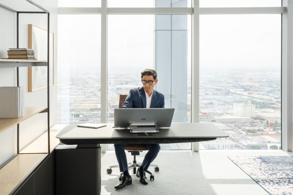 Un hombre sentado en un escritorio de oficina trabajando en un Surface Studio 2 Plus y un Surface Pro 9 en el escritorio junto a él. No se muestra ninguna pantalla.