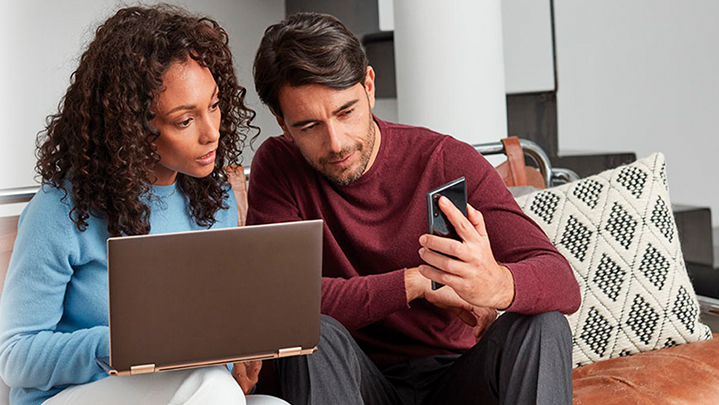 Un hombre y una mujer mirando una laptop y un teléfono