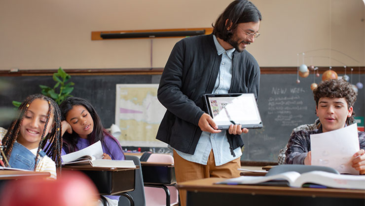 Homme tenant une tablette avec trois enfants autour de lui, assis sur des chaises