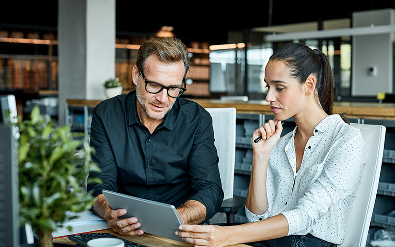 Homme et femme regardant une tablette en position assise