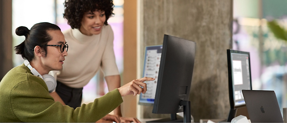 Deux individus collaborant sur un ordinateur, concentrés sur leur travail ensemble.