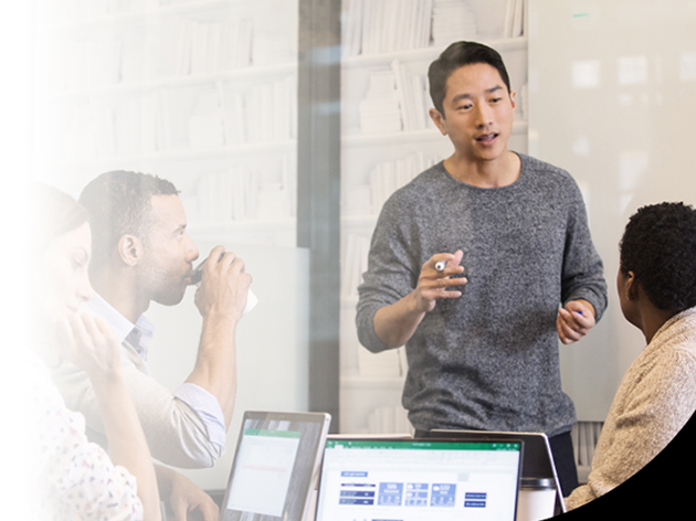 Seorang laki-laki sedang presentasi di depan dua orang temannya dalam sebuah ruangan