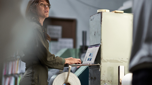 Seorang wanita sedang berdiri di depan laptop nya untuk bekerja