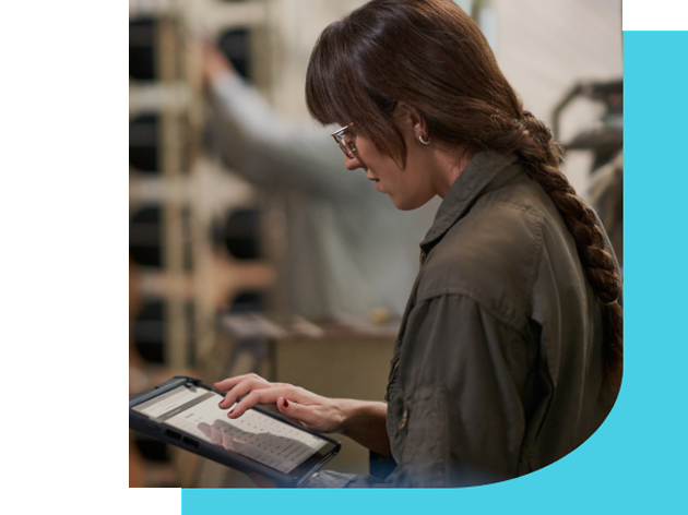 Seorang wanita berambut panjang dan mengenakan kacamata sedang bekerja mengggunakan laptopnya.