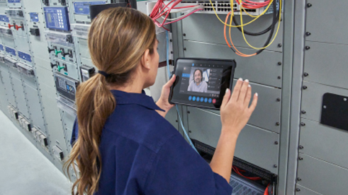 Seorang wanita sedang rapat online menggunakan tabletnya dalam sebuah ruangan server