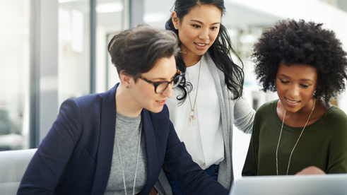 3 orang wanita sedang rapat dan duduk berdekatan mendiskusikan mengenai kerjaan