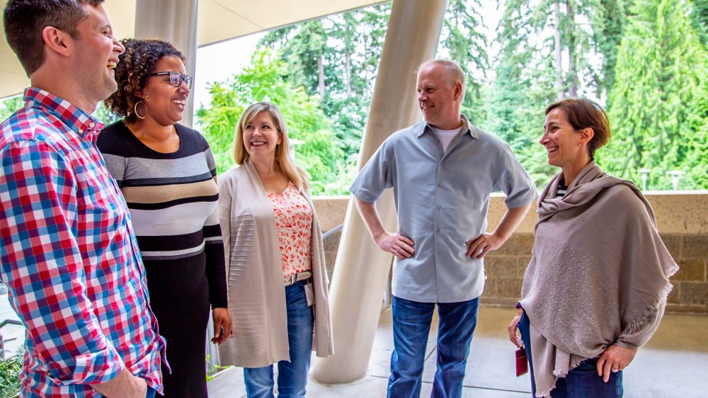 Bill Lincoln, Cassandra Young, Rebekah Hankins, Kurt Hughes, and Liz Friedman share a laugh in a photo taken outside.