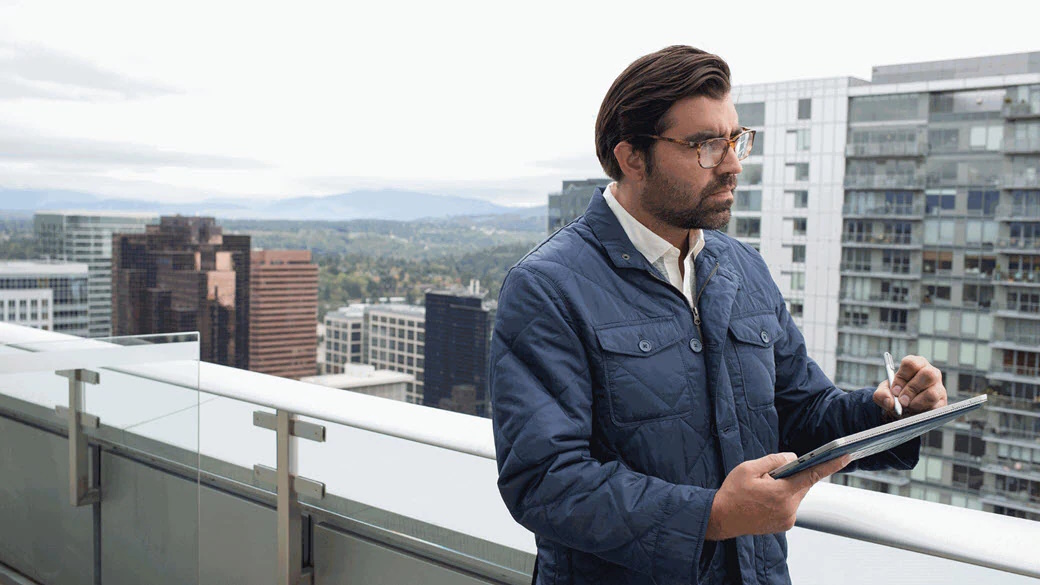 Businessman on office building rooftop with tablet.