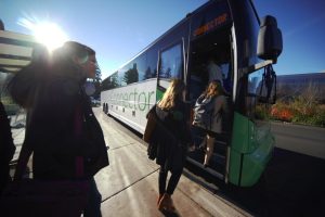 Microsoft employees walk onto a Connector bus on a sunny day,