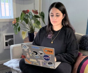 Tahira Al-Faham sits on the couch while on her laptop.