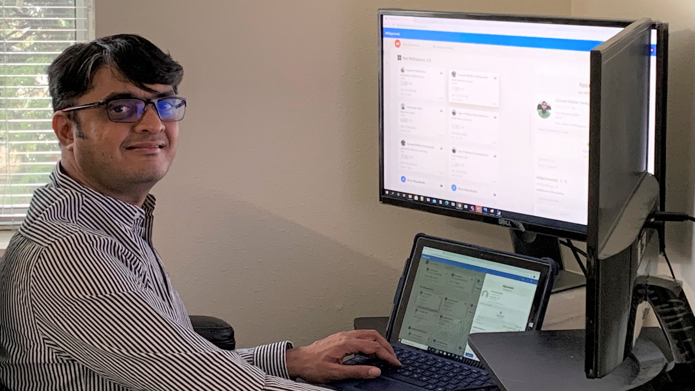 Nirav Khandhedia smiles while working at a desk in a home office.