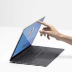 A person uses their finger to push open their laptop.