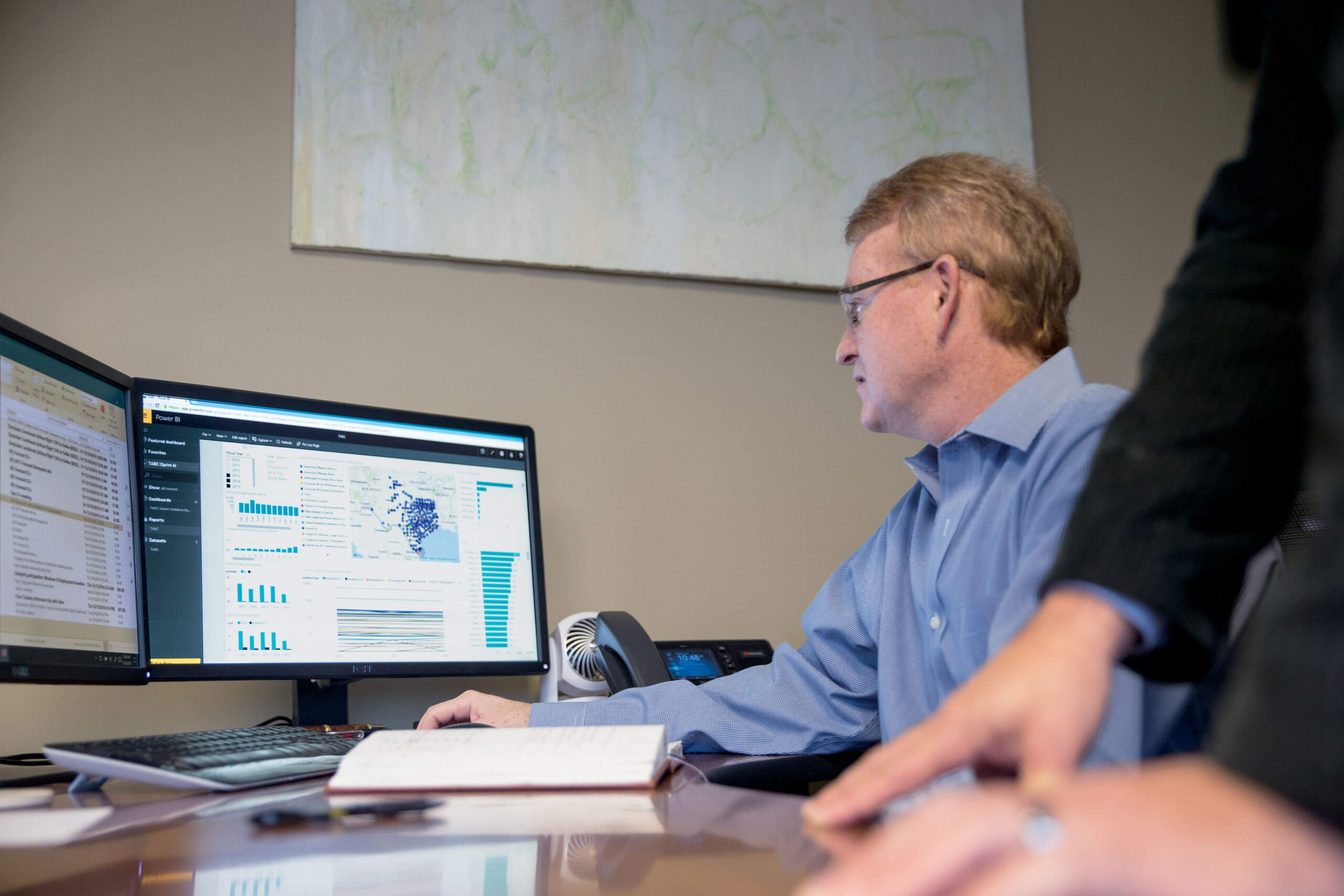 A Microsoft employee works on a Power BI dashboard displaying geographic information.