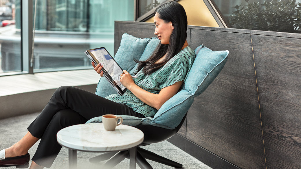 A Microsoft employees reads a tablet in a sitting area in the open space of a Microsoft building.