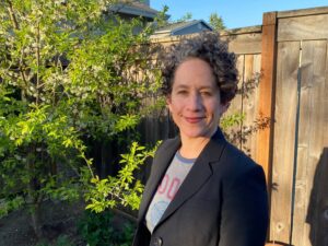 Fishkind smiles in a photo taken in front of some greenery and a wooden fence.