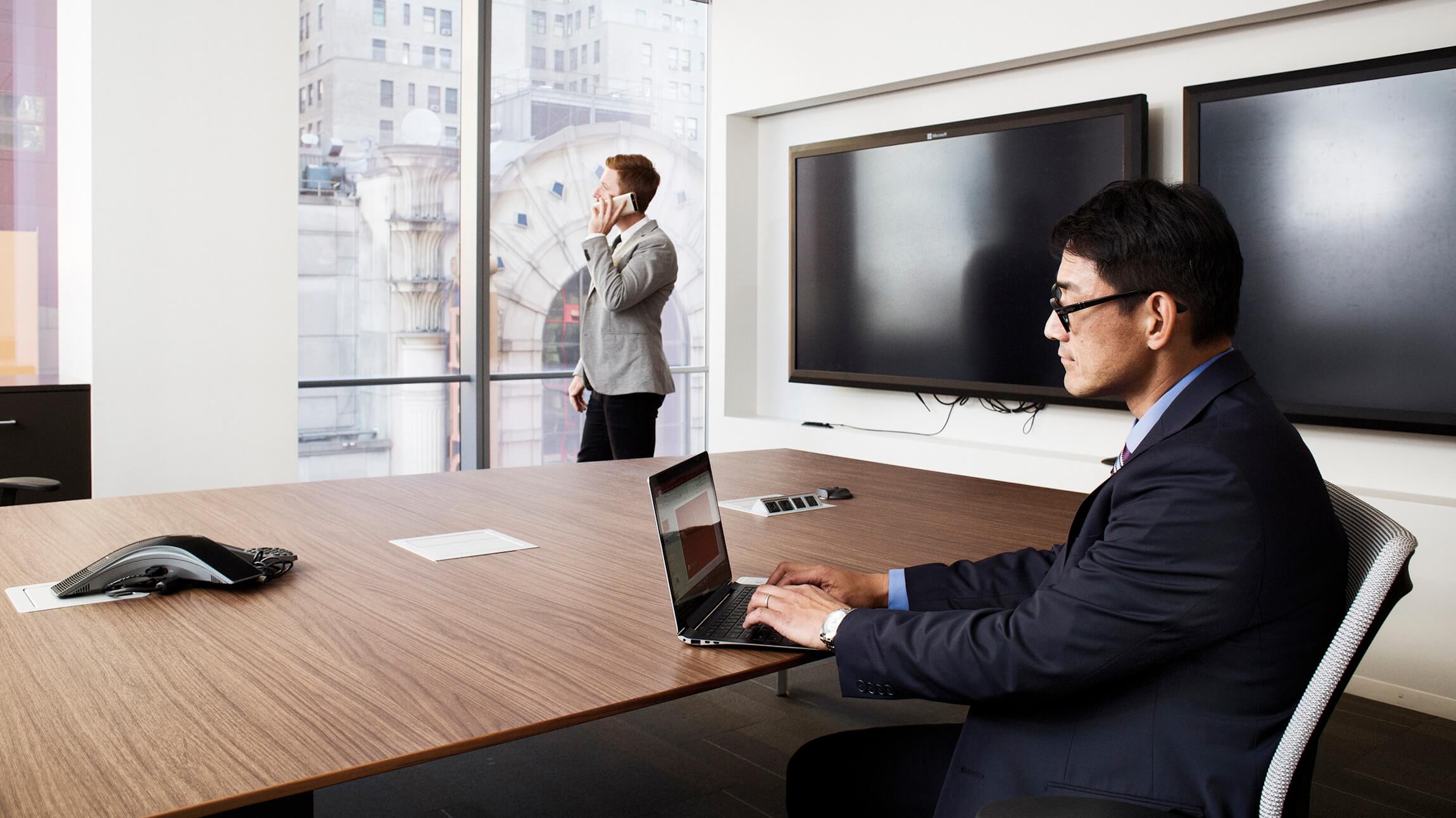 A businessman using a laptop in a conference room.