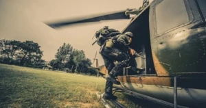 ヘリコプターに銃を携行して乗り込む兵士