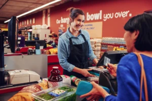 スーパーマーケットのレジで会計をする女性店員と女性客