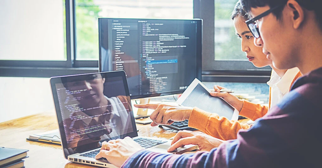 画面を見ながらプログラムを確認する男女のプログラマー