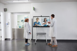 Surface Hub 2 スマート カメラを搭載した Hub 2S に表示された Microsoft Teams を通じて、2 人の医療従事者が 2 人の看護師と話している様子