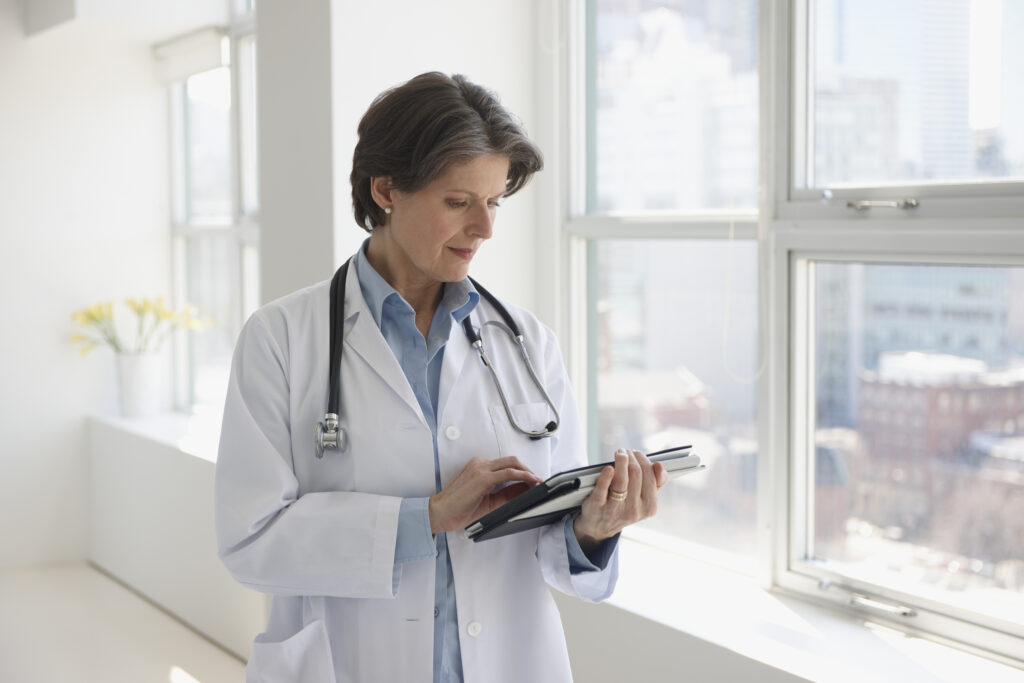 Female doctor looking at her clinical notes on a tablet.