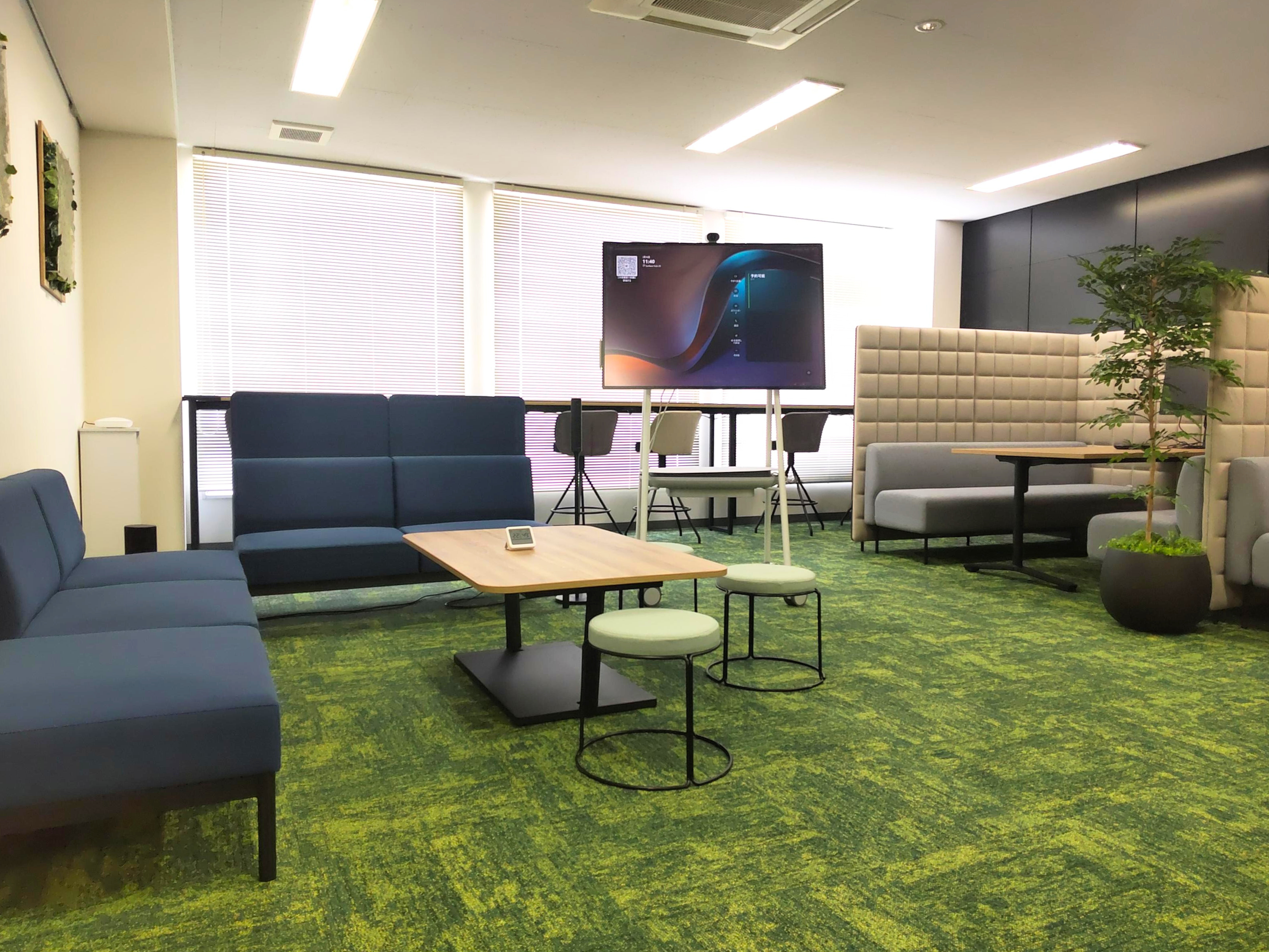 緑のカーペットとソファ、移動式スクリーンがあるくつろぎスペース。