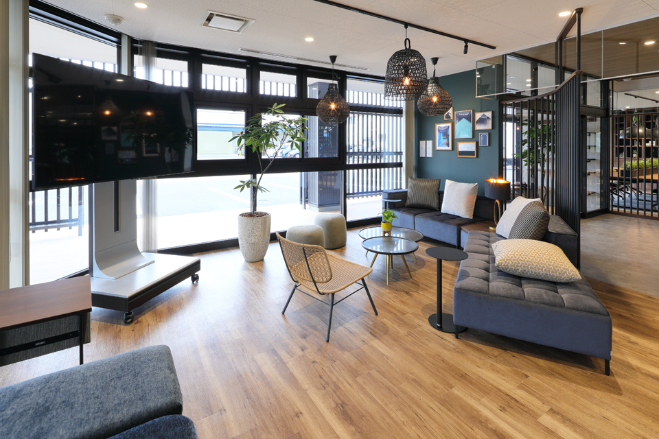 大型テレビとソファ、おしゃれな照明があるモダンなラウンジ空間。