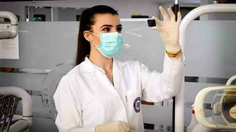 A healthcare worker in a lab coat and face mask inspects a scan.