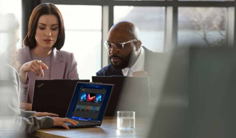 Profissionais em reunião corporativa analisando conteúdos em laptops em um escritório moderno.