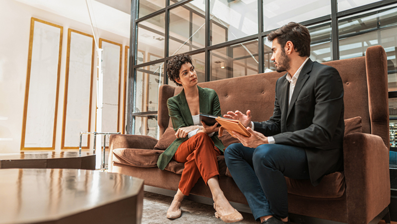 um homem e uma mulher sentados em um sofá conversando durante uma entrevista de emprego
