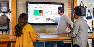 Um homem e uma mulher apontando para o monitor