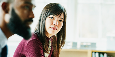 Uma mulher olhando um homem falando em uma sala de reunião