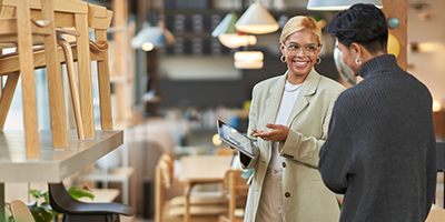Vendedora segurando tablet e sorrindo para um cliente