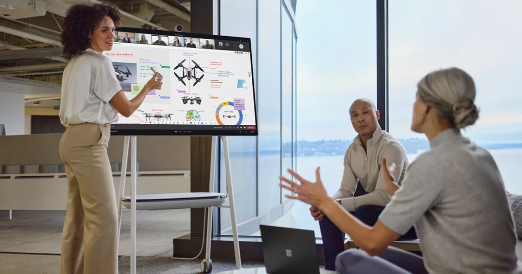 Uma mulher diante de uma apresentação, falando com colegas