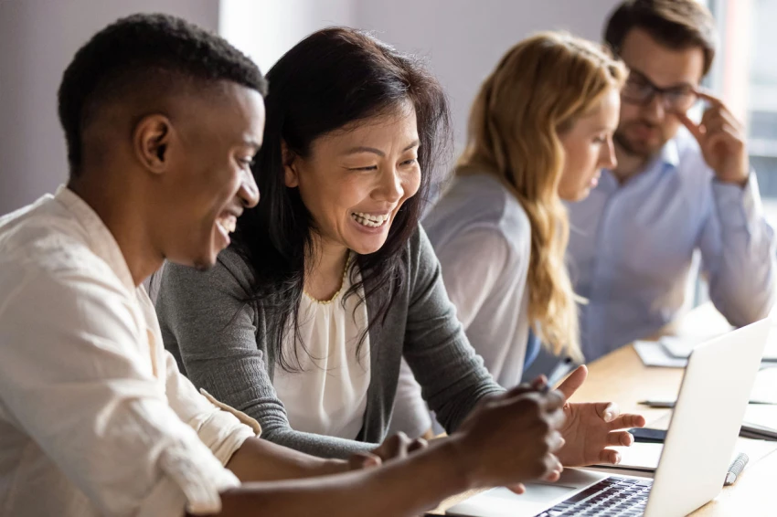 Empres&aacute;ria madura e feliz discutindo um projeto no laptop com uma jovem colega