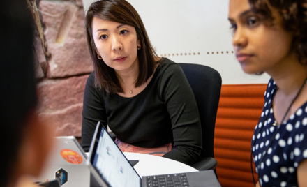 Image of several employees gathered around a desk.