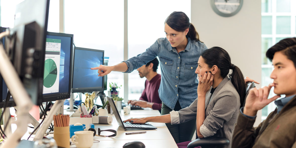 Image of coworkers pointing at a computer monitor.