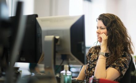 Adult woman sitting behind a computer screen.