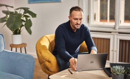 Adult male working from coffee table on Dell laptop.
