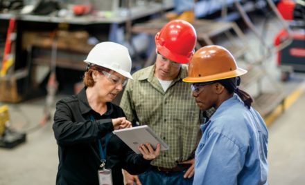 CEO of large manufacturing company discussing a project with operations manager and foreman.