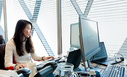 Image for: Image of an office worker looking at her computer monitors.