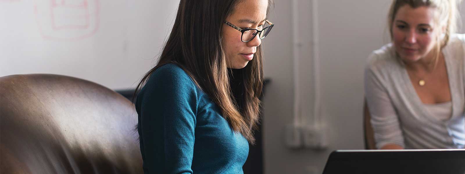 業務人員向一旁顧客用筆記型電腦展示資訊的照片圖示